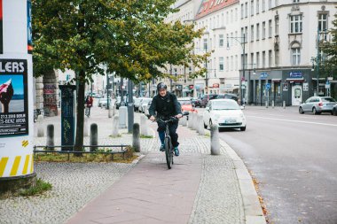 Berlin, 12 Aralık 2017: Yaşlı bir adam bir scooter üzerinde bir özel bisiklet yol boyunca şehrin bina, yol, araba yanındaki sokak sürmek. Şehrin her yerinde ulaşım araçlarının çevre dostu.