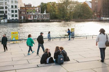 Berlin, 3 Ekim 2017: Bir grup genç kız arkadaşıyla ünlü Berlin duvarının bulunan ve birbirleri ile iletişim Waterfront oturan öğrencilerin.