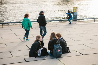 Berlin, 3 Ekim 2017: Bir grup genç kız arkadaşıyla ünlü Berlin duvarının bulunan ve birbirleri ile iletişim Waterfront oturan öğrencilerin.