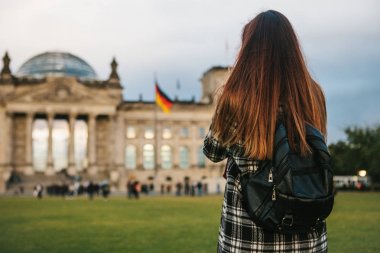 Bir turist kız Almanya'da Berlin Reichstag denilen binanın yanındaki bir sırt çantası ile fotoğraf çeker. Gezi, turizm.