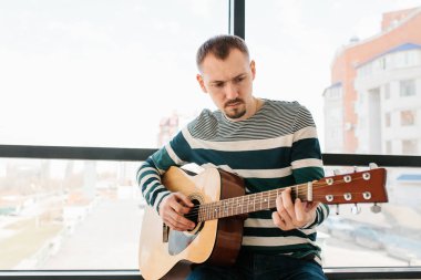 Bir adam gitar çalıyor. Gitar çalmayı öğrenme. Müzik eğitimi.
