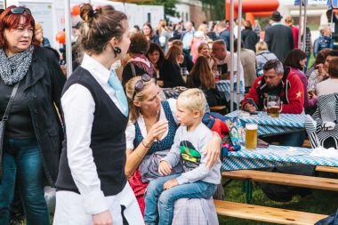 Prag, 23 Eylül 2017: Oktoberfest denilen geleneksel Alman Bira Festivali kutluyor. Güzel bir ulusal kostüm bir kadının anne çocuğunu yatıştırır. Çocuk üzgün.
