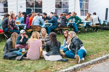 Prag, 23 Eylül 2017: Oktoberfest denilen geleneksel Alman Bira Festivali kutluyor. Genç Kız konuşuyor ve taze bira içme çimenlerin üzerinde oturan arkadaşlar