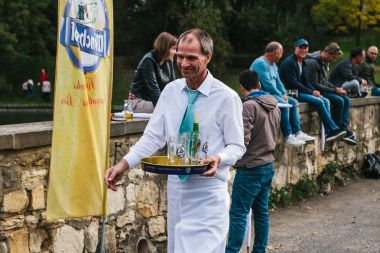 Prag, 23 Eylül 2017: Oktoberfest denilen geleneksel Alman Bira Festivali kutluyor. Boş şişeleri ve kupalar dostu gülümseyen garson toplar.