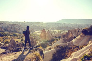 Bir gezgin bir sırt çantası ile şapkalı bir dağda duruyor ve Kapadokya Türkiye'de güzel bir görünüm bakar. Yolculuk. Hiking.