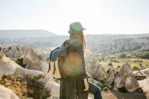 Een reiziger in een hoed met een rugzak staat op een berg en kijkt naar een prachtig uitzicht in Cappadocië in Turkije. Reis. Wandelen. — Stockfoto