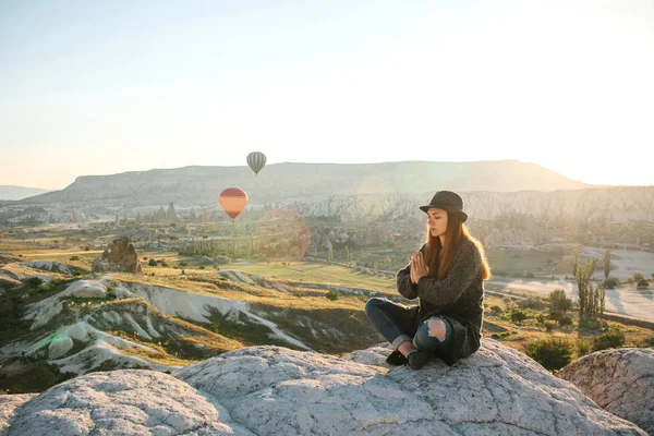 Young beautiful girl practicing yoga at the top of a mountain in Cappadocia at sunrise. Practices of relaxation. — Stock Photo, Image