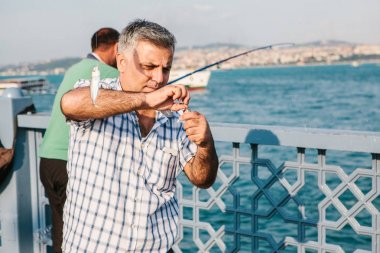 Istanbul, 15 Haziran 2017: Galata Köprüsü ve balıklar üzerinde yerel halkın duruyor üzerinden bir balıkçı. Istanbul sakinlerinin geleneksel hobi.