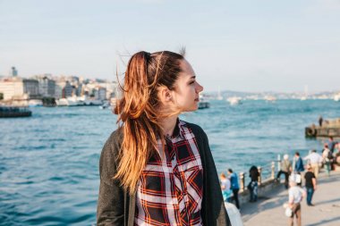 Güzel genç kadın Istanbul'da güzel manzaralarına sahiptir. İnsanlar, şehir yapı ve boğaz yelken gemi arka planda bulanık. Türkiye'de tatil