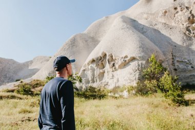 Adam güzel kayaların yanında duruyor ve Kapadokya Türkiye'de sahne hayran. Kapadokya'nın peyzaj. Tepeler.