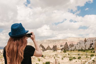 Bir turist kız telefonda hills Kapadokya Türkiye'de güzel bir manzarasına anısına bir fotoğraf yapar. Seyahat, turizm, hiking tatil.
