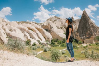Kadın güzel kayaların yanında duruyor ve peyzaj Kapadokya Türkiye'de hayran. Kapadokya'nın peyzaj.