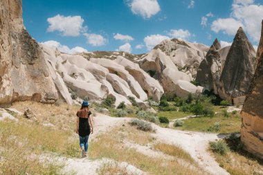 Bir turist kız harika tepeler Türkiye'de Kapadokya'nın yanında yol boyunca yürür ve çevresinde güzellik hayran. Kapadokya'nın peyzaj.