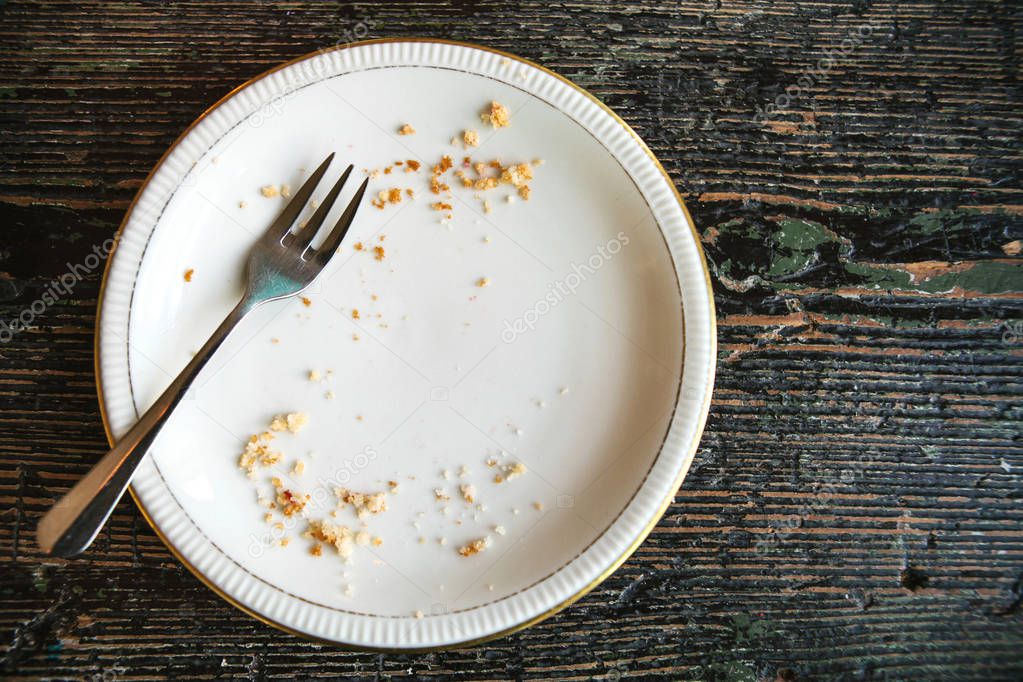 Conceptual image of the end of the holiday is an empty plate with crumbs and a fork on it.