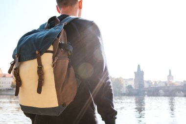 Bir sırt çantası ile bir genç turist adam Prag'da Vltava Nehri yanındaki duruyor ve şehir'in mimaride hayran. Çek Cumhuriyeti seyahat.