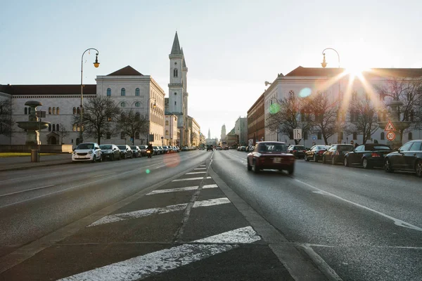 Vista de la carretera en la calle Leopoldstrasse en Munich, la capital de Baviera en Alemania. Rápido coche de movimiento borroso en el fondo del atardecer . — Foto de Stock