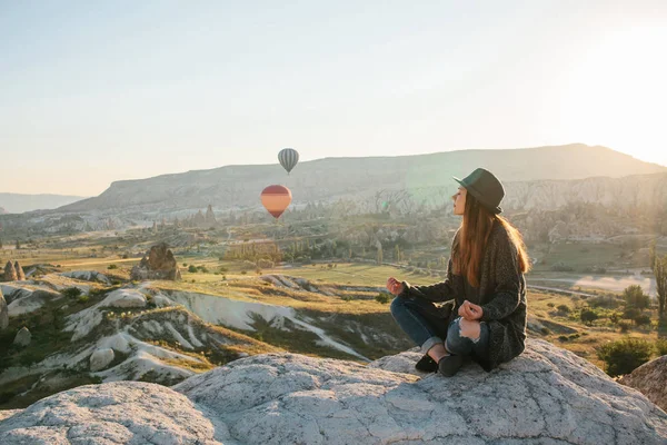 Young beautiful girl practicing yoga at the top of a mountain in Cappadocia at sunrise. Practices of relaxation. — Stock Photo, Image