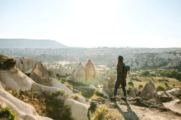 Bir gezgin bir sırt çantası ile şapkalı bir dağda duruyor ve Kapadokya Türkiye'de güzel bir görünüm bakar. Yolculuk. Hiking.