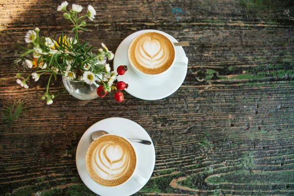 Vista superior de dos tazas de café y un florero sobre una mesa de madera. Una foto significa una reunión o una fecha . — Foto de Stock