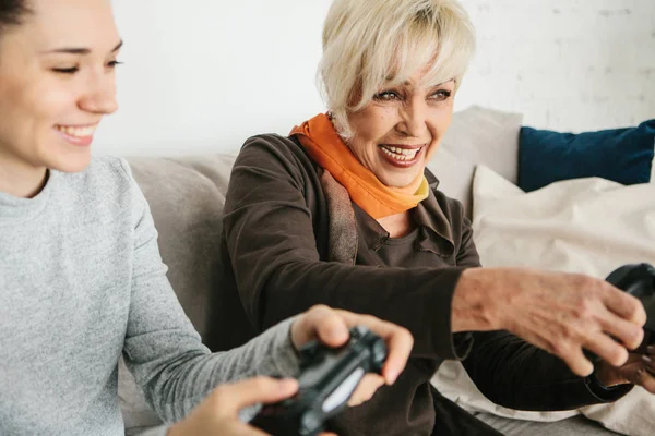A young girl and an elderly woman play together in a video game. Joint pastime. Family life. Communication of the grandmother with her granddaughter.