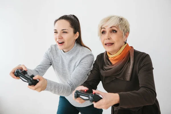 Una joven y una anciana juegan juntas en un videojuego. Pasatiempo común. Vida familiar. Comunicación de la abuela con su nieta . —  Fotos de Stock