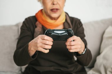 Yaşlı bir kadın video oyun oynuyor. Yaşlı kişi ve modern teknoloji.