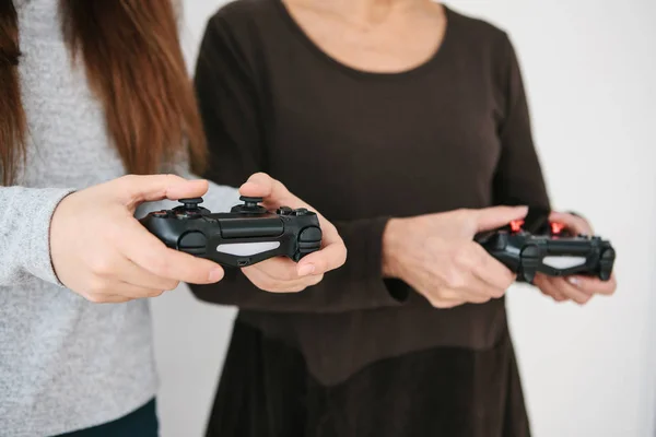 A young girl and an elderly woman play together in a video game. Joint pastime. Family life. Communication of the grandmother with her granddaughter.