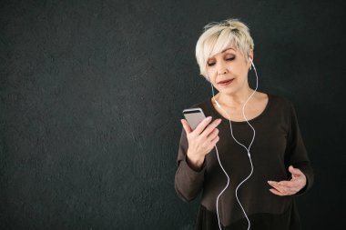 Müzik pozitif yaşlı kadın. Karanlık bir arka plan üzerinde. Eski nesil ve yeni teknolojiler.