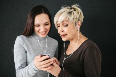 Yaşlı bir kadın ve genç bir kız birlikte müzik dinlemek. İnsanlar farklı nesillerin arasında iletişim.