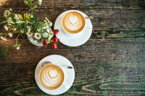 Vista superior de dos tazas de café y un florero sobre una mesa de madera. Una foto significa una reunión o una fecha . — Foto de Stock