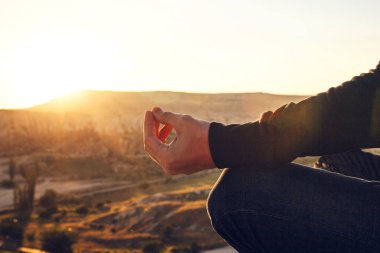 Bir adam güneş doğarken dağın zirvesine yoga uygulamaları. Gevşeme uygulamaları.