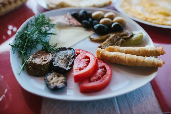 Szczelnie-do góry. Śniadanie na talerzu składający się z pomidora, sera, rolki, czarne i zielone oliwki i bakłażana. — Zdjęcie stockowe