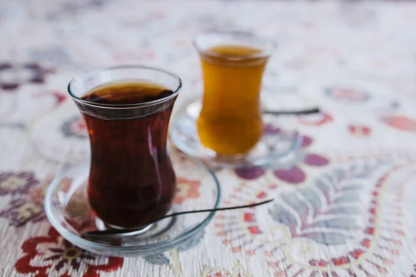 На столе стоят два традиционных турецких чая с тюльпановыми кружками. Ложки на тарелках. Вкусный и здоровый напиток . — стоковое фото