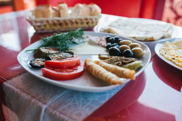 Detail. Snídaně na desce skládající se z rajčat, sýra, roll, černé a zelené olivy a lilek. — Stock fotografie