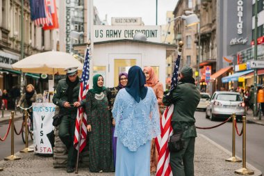 Berlin, 1 Ekim 2017: Pozitif huzurlu neşeli güzel Arap kadınlar geleneksel kostümleri iletişim ve checkpoint Charlie yanında Amerikan askerleri ile fotoğraf çekmek