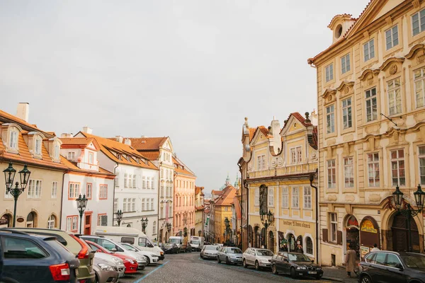 Praga, 20 de diciembre de 2017: Hermosa calle de Praga con arquitectura antigua, adoquines, letreros publicitarios y numerosos aparcamientos de coches a lo largo de las casas — Foto de Stock