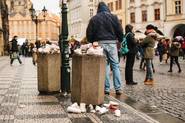 Prague, December 24, 2017: A crowded trash can on Pragues main square during the christmas holidays. A lot of people in the square. Pollution of city streets with trash on holidays.
