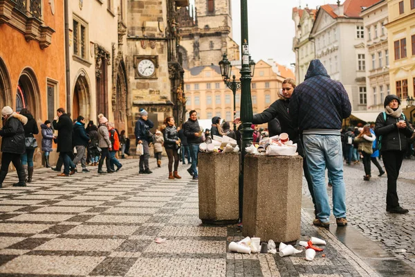 Praga, 24 de diciembre de 2017: Un cubo de basura lleno de gente en la plaza principal de Pragues durante las vacaciones de Navidad. Mucha gente en la plaza. Contaminación de las calles de la ciudad con basura en vacaciones . — Foto de Stock
