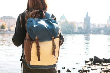 Bir sırt çantası bir güzel genç turist kızla Prag'da Vltava Nehri yanındaki duruyor ve Charles Köprüsü denilen en popüler konumlar hayran. Çek Cumhuriyeti seyahat.