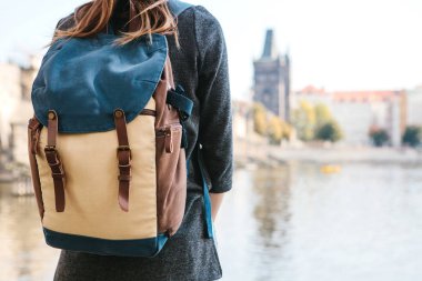 Bir sırt çantası bir güzel genç turist kızla Prag'da Vltava Nehri yanındaki duruyor ve Charles Köprüsü denilen en popüler konumlar hayran. Çek Cumhuriyeti seyahat.