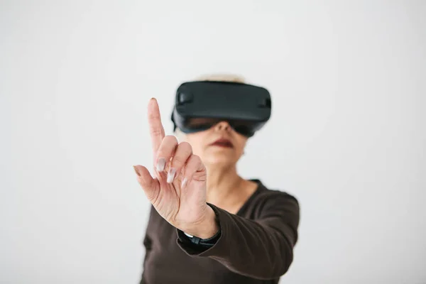 An elderly woman in virtual reality glasses. An elderly person using modern technology. — Stock Photo, Image