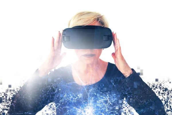 Пожилая женщина в очках виртуальной реальности разбросана по пикселам. Концептуальная фотография с визуальными эффектами пожилого человека с использованием современных технологий . — стоковое фото