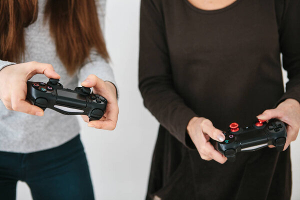 A young girl and an elderly woman play together in a video game. Joint pastime. Family life. Communication of the grandmother with her granddaughter.