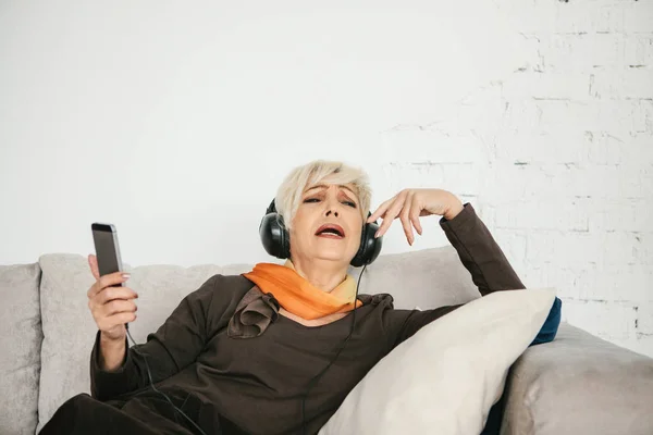Una anciana positiva escucha música y canta. La generación más antigua y las nuevas tecnologías. — Foto de Stock