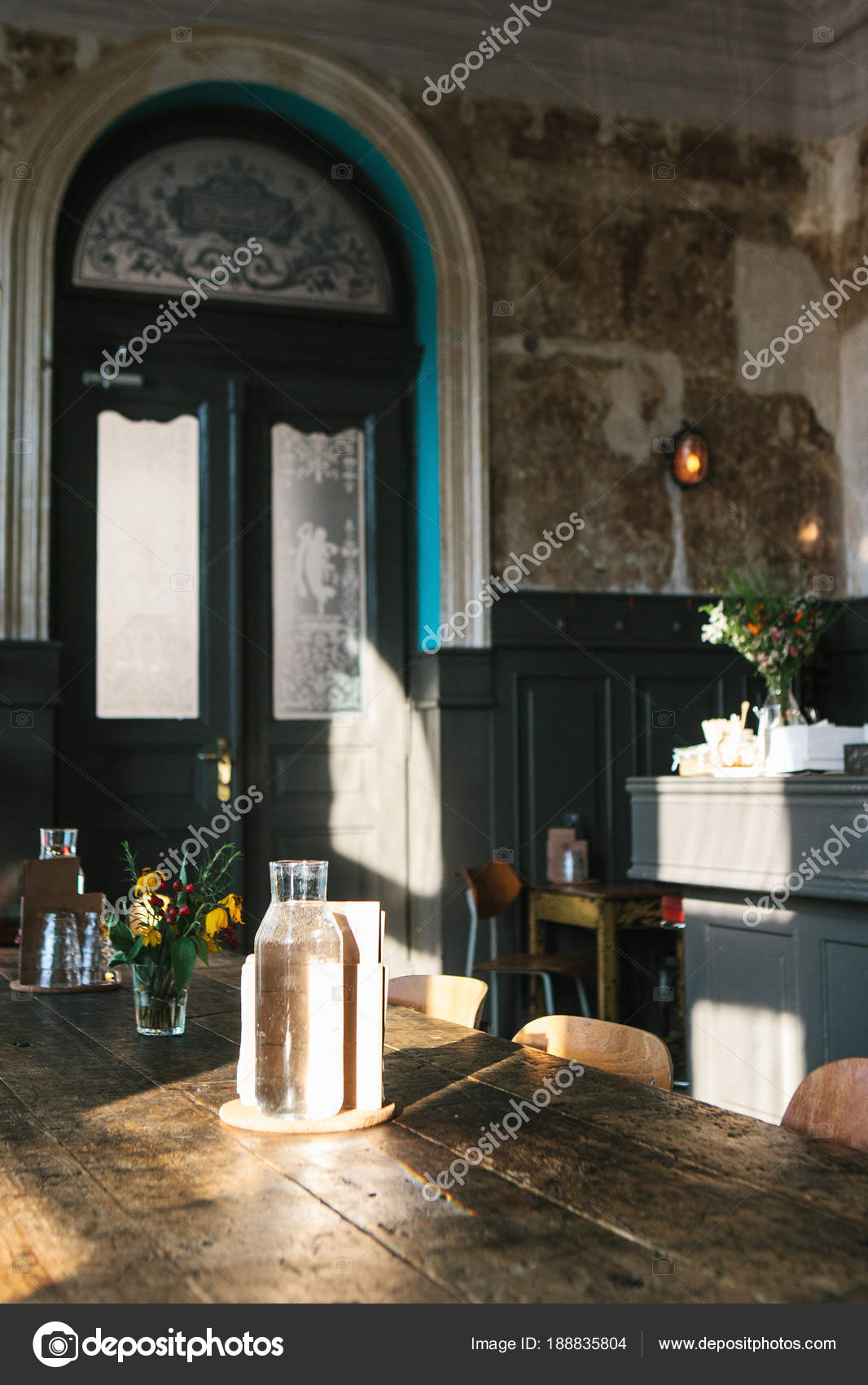 An Empty Vase And A Nearby Vase Of Flowers On A Wooden Table