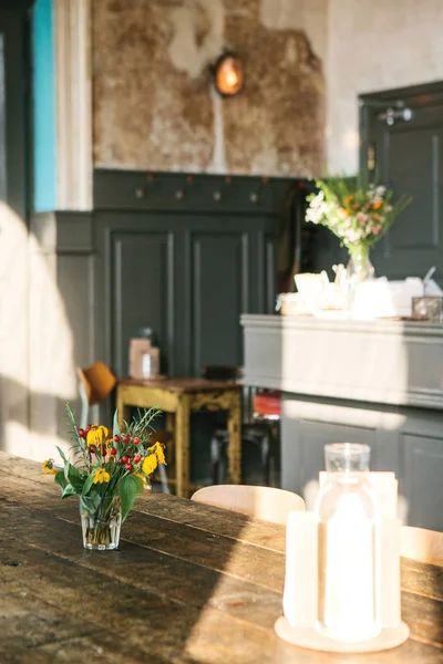 Un jarrón con flores y un florero vacío cercano para decoraciones en una mesa de madera. Fotografía vertical . —  Fotos de Stock