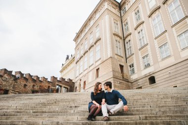 Sevgi dolu genç güzel bir çift Avrupa'dan öğrenci Prag ve konuşmaya binalarda yanında merdivenlerde oturuyor. Hisler ve duygular insanlar arasında kapatın.