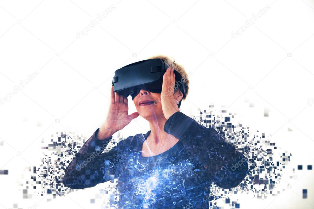 An elderly woman in virtual reality glasses is scattered by pixels. Conceptual photography with visual effects with an elderly person using modern technology.