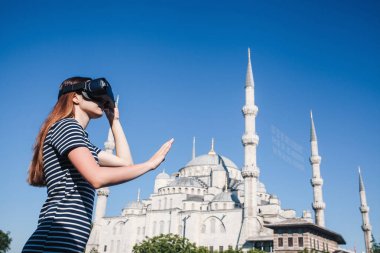 Sanal gerçeklik gözlüklü bir gezgin. Dünyanın dört bir yanından sanal seyahat kavramı. Arka planda Türkiye'de Istanbul'da Sultanahmet Camii. Geleceğin teknolojisi kavramı.
