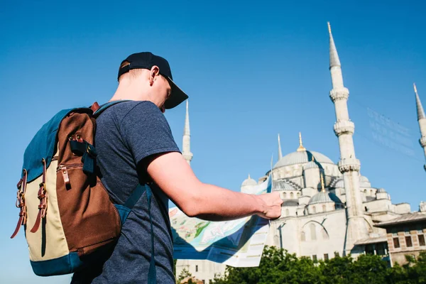 Cestovatel v baseballovou čepici s batohem se dívá na mapě vedle modré mešity - slavný pohled z Istanbulu. Cestování, Turistika, Památky. — Stock fotografie